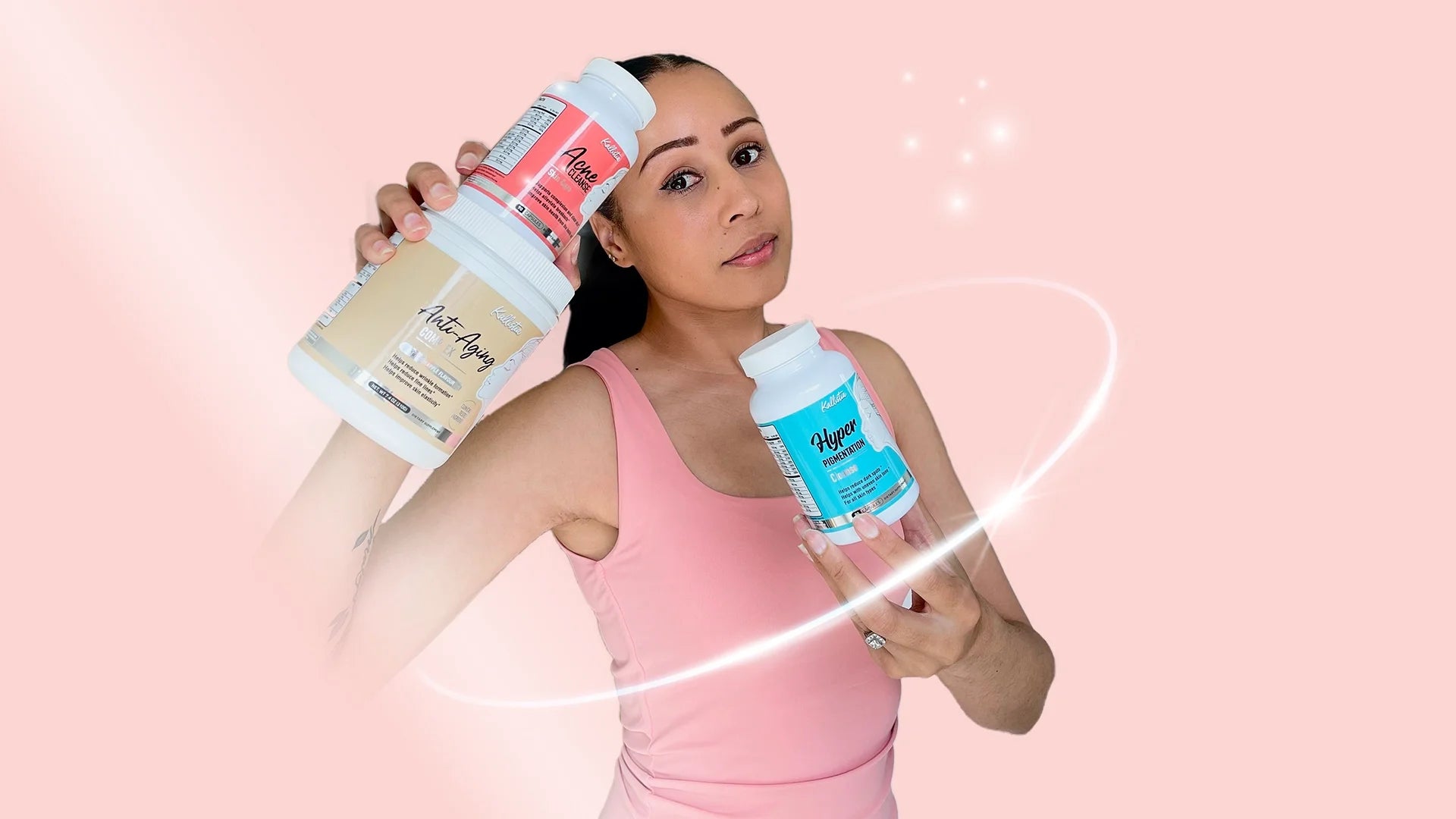Woman in a pink tank top holding two Kallistia supplement jars - Anti-Aging and Acne Cleanse in her raised left hand, and Hyper Pigmentation capsules in her right hand - against a soft pink glowing background with a white light swirl effect