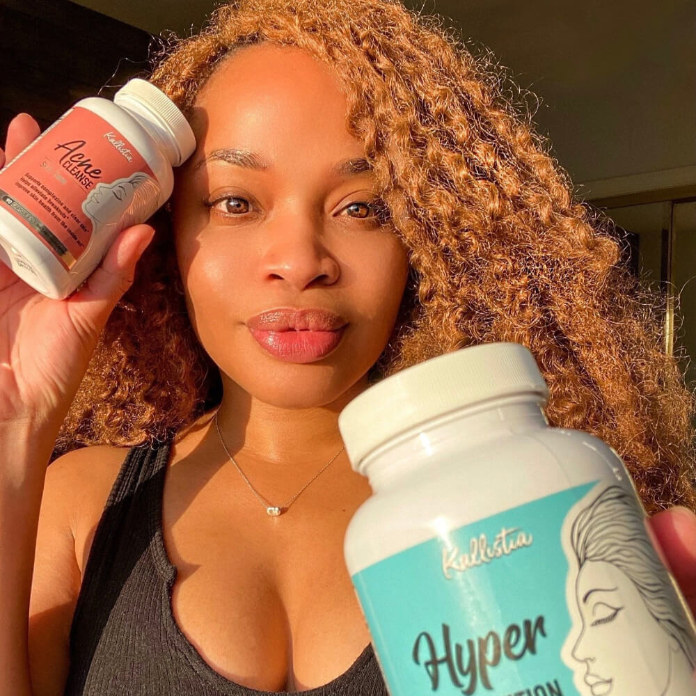 Woman holding two supplement bottles labeled Acne cleanse and hyperpigmentation cleanse